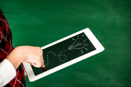 School kid in class. Hands holding tablet PC against green blackboard. Education conceptの写真素材