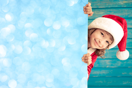 Child holding empty banner. Kid hiding behind card blank. Christmas Xmas winter holiday conceptの写真素材