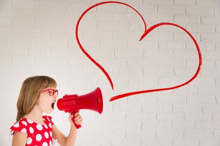 Child girl shouting by retro megaphone. Valentines day conceptの写真素材