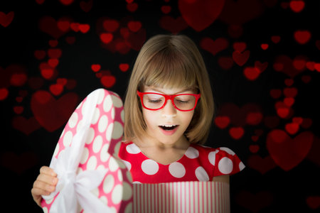 Happy girl open gift box with red heart against dark background. Valentines day conceptの写真素材