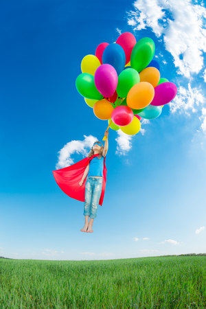 kid with multicolor balloons outdoor against blue sky.の写真素材