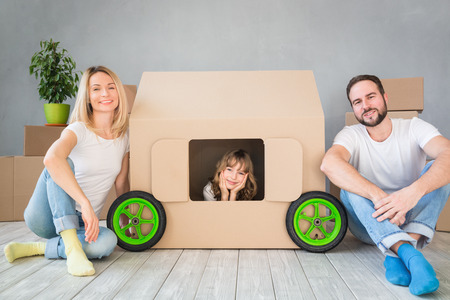 Happy family playing into new home. Father, mother and child having fun together. Moving house day and real estate conceptの写真素材