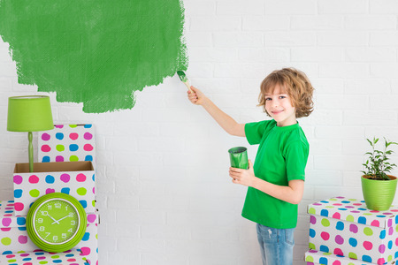Happy child painting the wall with green color. Kid having fun at home. Spring renovation conceptの写真素材