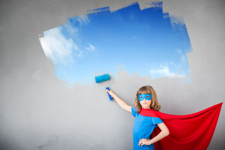 Superhero child painting the wall with blue color. Kid having fun at home. Spring renovation conceptの写真素材