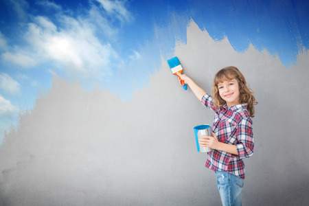 Happy child painting the wall with blue color. Kid having fun at home. Spring renovation conceptの写真素材