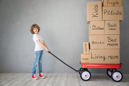 Happy child playing into new home. Kid having fun indoor. Moving house day and express delivery...