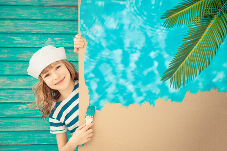 Happy sailor child painting the cardboard with blue color. Kid having fun at home. Spring renovation conceptの写真素材