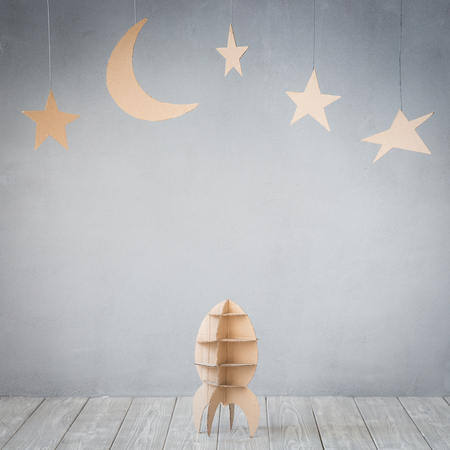 Cardboard rocket and stars against grey concrete wall backgroundの写真素材