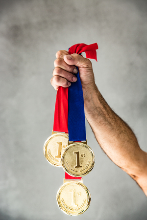 Senior man holding medal in hand. Win and success conceptの写真素材