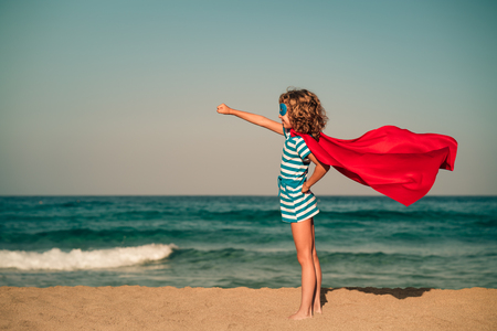 Superhero child on the beach. Super hero kid having fun outdoor. Summer vacation conceptの写真素材