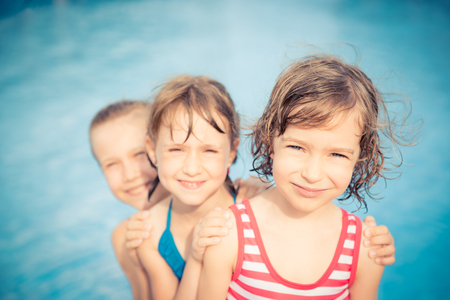Happy children in the swimming pool. Funny kids playing outdoors. Summer vacation conceptの写真素材