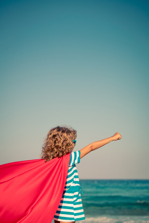 Superhero child on the beach. Super hero kid having fun outdoor. Summer vacation conceptの写真素材