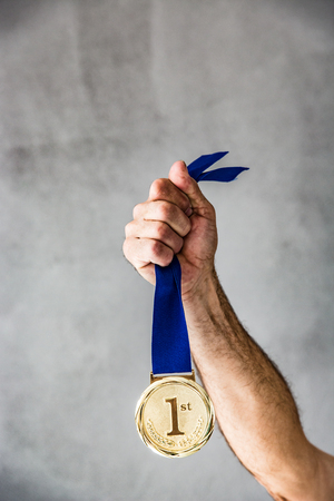 Senior man holding medal in hand. Win and success conceptの写真素材