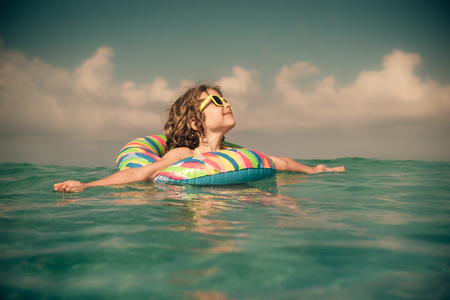 Happy child playing in the sea. Kid having fun at the beach. Summer vacation and active lifestyle conceptの写真素材