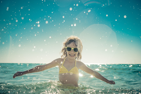 Happy child playing in the sea. Kid having fun at the beach. Summer vacation and active lifestyle conceptの写真素材