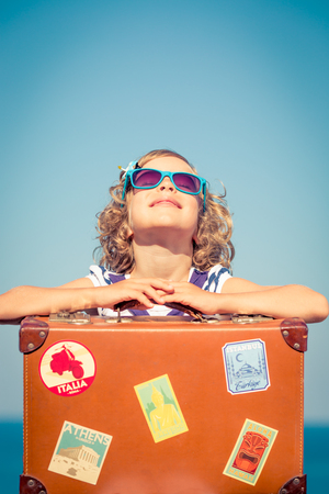 Happy child with vintage suitcase. Kid having fun on summer vacation. Travel and adventure conceptの写真素材