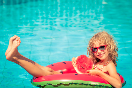 Child with watermelon outdoor. Kid having fun in swimming pool. Summer vacation and healthy eating conceptの写真素材