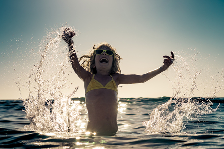 Happy child playing in the sea. Kid having fun at the beach. Summer vacation and active lifestyle conceptの写真素材