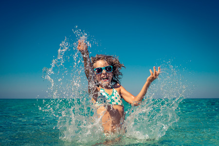 Happy child playing in the sea. Kid having fun at the beach. Summer vacation and active lifestyle conceptの写真素材