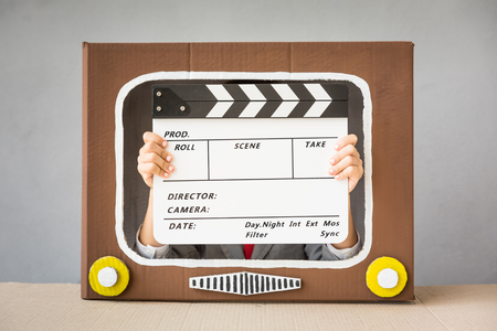 Child playing with cardboard box TV. Kid having fun at home. Video blogging conceptの写真素材