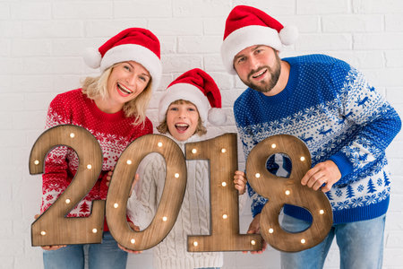Happy New Year! Family having fun at home. People holding numbers 2018