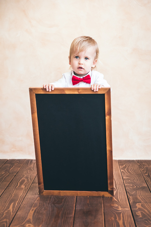 School kid in class. Funny child holding blackboard. Education conceptの写真素材