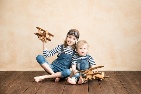 Happy children playing at home. Baby boy and girl with toy airplane. Summer vacation and travel, dream and imagination conceptの写真素材