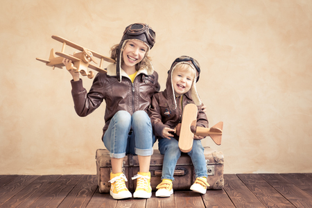 Happy children playing with vintage wooden airplane. Kids having fun at home. Imagination and freedom conceptの写真素材