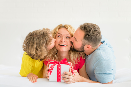 Man and child kissing woman. Mother, father and daughter having fun together. Spring family holiday concept. Mother's dayの写真素材