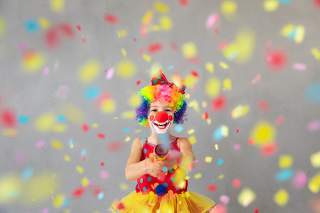 Funny kid clown with party poppers. Happy child playing at home. 1 April Fool's day conceptの写真素材