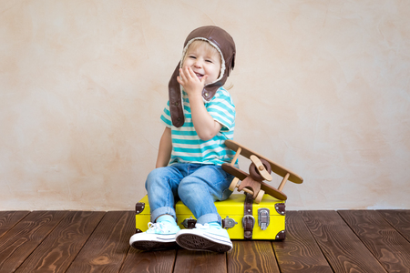 Happy child playing with vintage wooden airplane. Kid having fun at home. Imagination and freedom conceptの写真素材