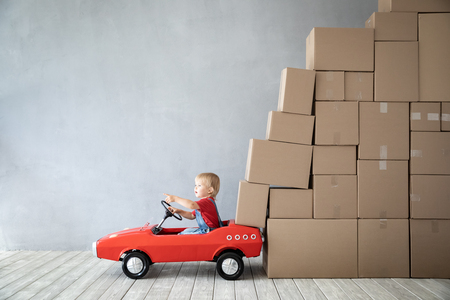 Happy child playing into new home. Kid driving toy car. Moving day conceptの写真素材