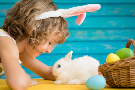 Child and Easter bunny. Kid playing with rabbit and eggs. Spring holidays concept