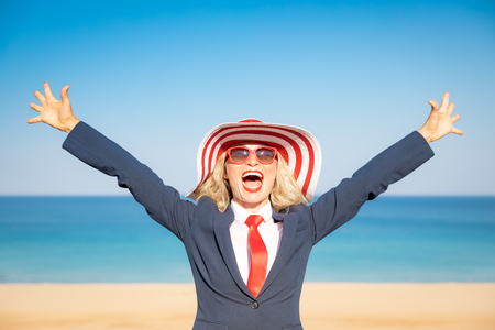 Successful businesswoman on the beach. Young woman against sea and sky background. Summer vacations and freedom travel conceptの写真素材