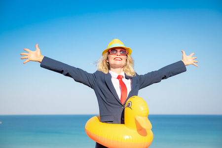 Successful businesswoman having fun on the beach. Young woman against sea and sky background. Summer vacations and freedom travel conceptの写真素材