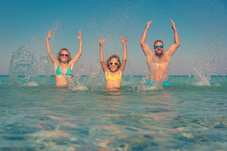 Happy family playing in the sea. Child; mother and father having fun on summer vacation. Healthy active lifestyle conceptの写真素材