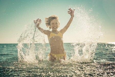 Happy child playing in the sea. Kid having fun on summer vacation. Healthy active lifestyle conceptの写真素材