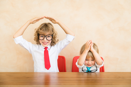 Happy children pretend to be businessmen. Funny kids playing at home. Education, start up and business idea conceptの写真素材