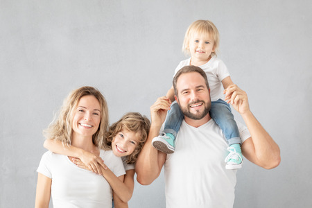 Portrait of happy family - father, mother, daughter and son - against grey background. Parents with children having fun at home.の写真素材