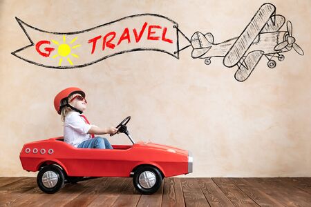 Happy child playing at home. Funny kid driving toy car indoor. Vacation and travel conceptの写真素材
