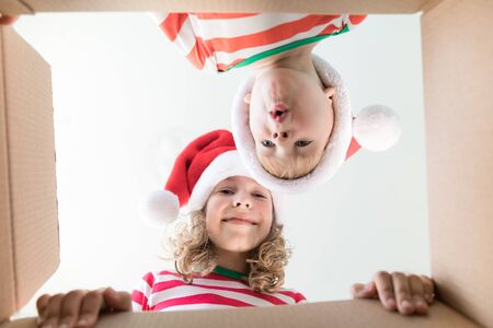 Happy children looking into the box. Funny surprised kids unpack Christmas gift box. Xmas holiday concept. Low angle view.の写真素材