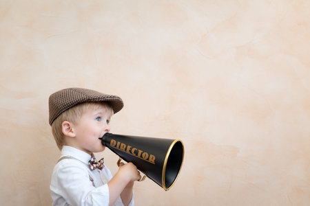 Child holding loudspeaker. Kid shouting through vintage megaphone. Business news concept