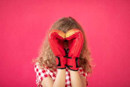 Happy girl with red heart shaped boxing gloves against pink background. Valentineâs day conceptの写真素材