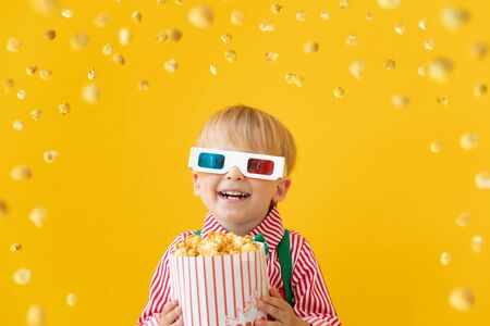 Happy child wearing 3d glasses. Surprised kid against yellow background. Cinema and movie time conceptの写真素材