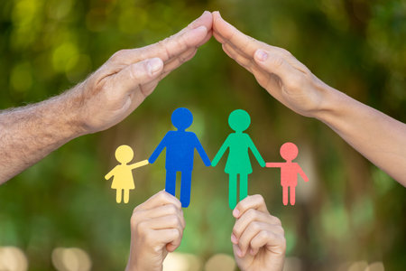 People holding paper family in hands against spring green background. Healthy lifestyle concept