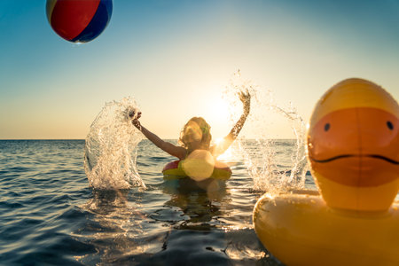 Child having fun on summer vacation. Kid playing in the sea at sunset. Active lifestyle concept....