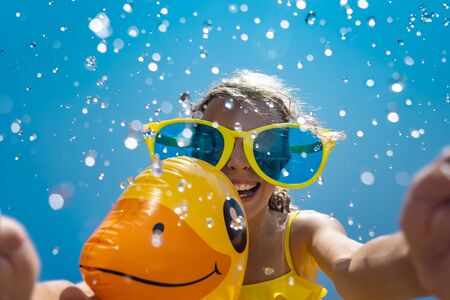 Child having fun on summer vacation. Kid playing with rubber duck in swimming pool. Spring break!の写真素材