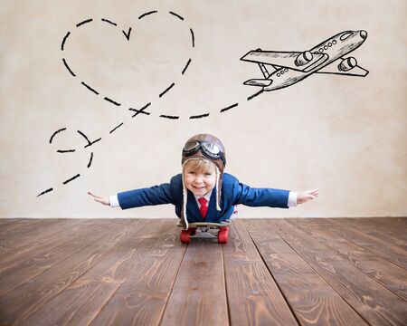 Portrait of young businessman riding on skateboard. Happy child playing at home. Kid having fun. Success, creative and travel conceptの写真素材