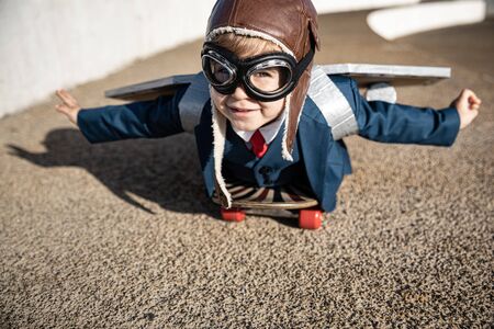 Funny child playing with toy wings. Happy kid having fun outdoor. Childhood dream and imagination conceptの写真素材