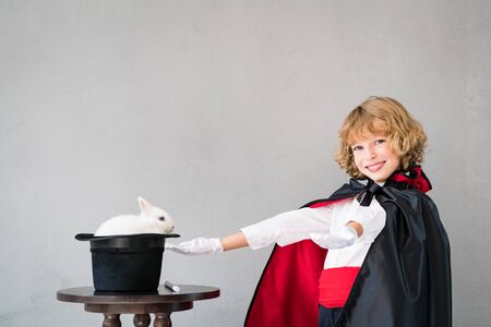 Child magician with cute rabbit. Happy kid playing at home. Imagination and magic trick conceptの写真素材